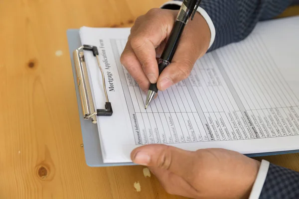 Hand füllen Hypothekendarlehen Antrag auf einem Klemmbrett aus. eine Form t — Stockfoto