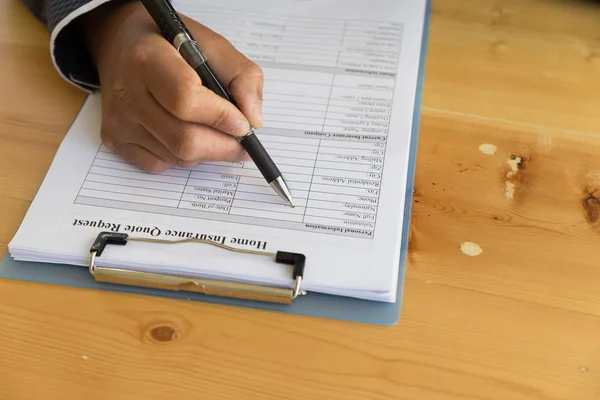 Hand füllen Sie das Formular für die Hausversicherung auf einem Klemmbrett aus - Immobilien — Stockfoto
