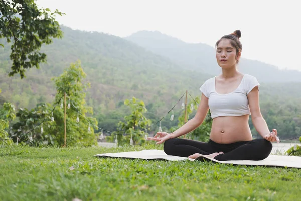 Asiatische schwangere Frau praktiziert Yoga, während sie in Lotus Posi sitzt — Stockfoto