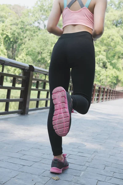Female sport fitness runner jogging outdoors on bridge in spring