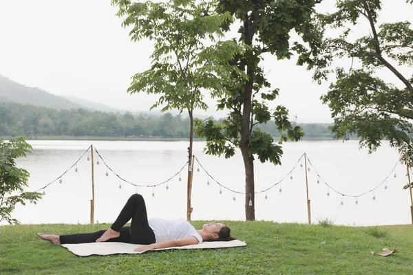 Asiático embarazada mujer practicando yoga en verde hierba en público pa — Foto de Stock