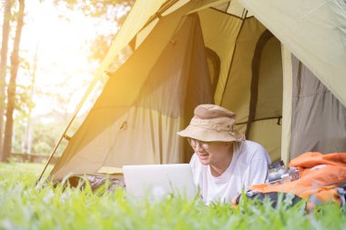 yalan ve çadır kamp yerinde dizüstü kullanarak genç adam turizm