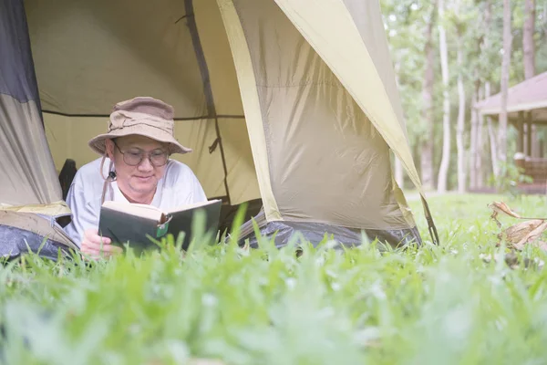 Jovem turista mentir e ler livro na tenda no local de acampamento — Fotografia de Stock