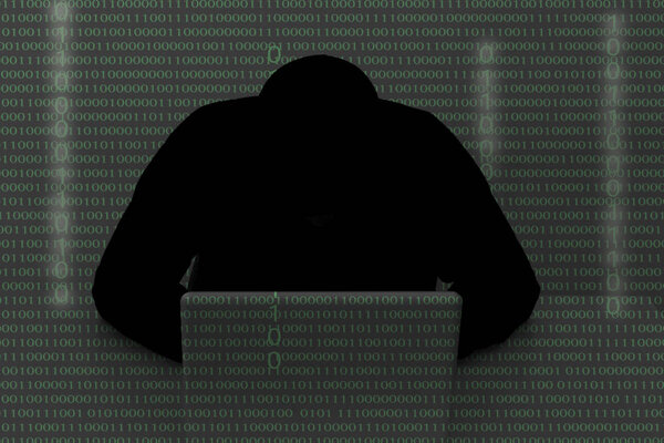 hacker wearing a hooded top using laptop computer in the dark. T