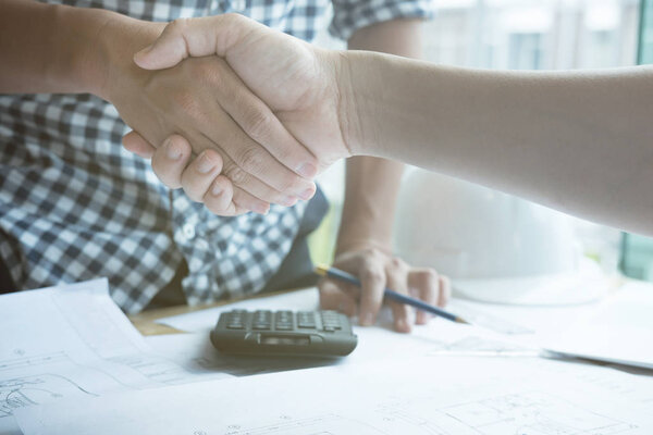 Architect and customer shaking hands at workplace. Engineer hand