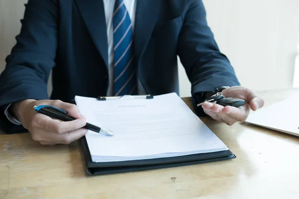 Hombre de negocios presente firma contrato de venta con llave de coche a custo — Foto de Stock