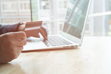 erkek bir kredi kartı tutan ve dizüstü bilgisayar için çevrimiçi kullanarak 