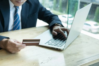 erkek bir kredi kartı tutan ve dizüstü bilgisayar için çevrimiçi kullanarak 