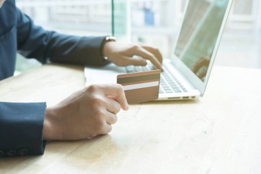 erkek bir kredi kartı tutan ve dizüstü bilgisayar için çevrimiçi kullanarak 