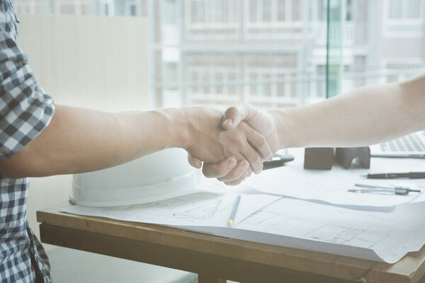 Architect and customer shaking hands at workplace. Engineer hand