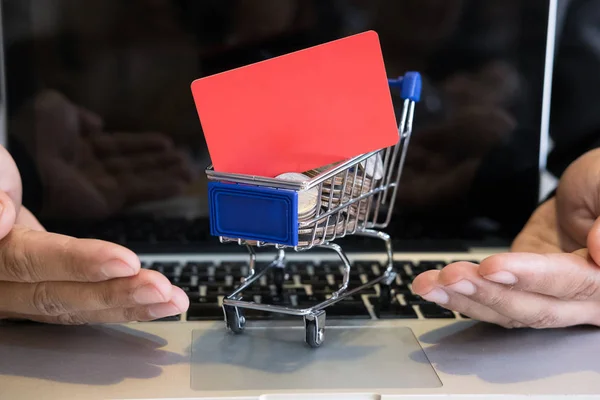 male showing a credit card in mini supermarket cart trolley full