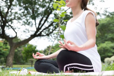 Yogada genel park açık havada. Asyalı kadın lotus bulunduğu oturur