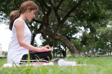 Yogada genel park açık havada. Asyalı kadın lotus bulunduğu oturur