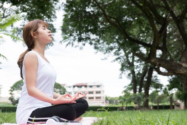 Yogada genel park açık havada. Asyalı kadın lotus bulunduğu oturur