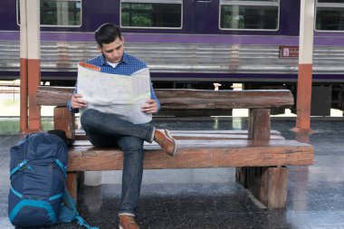 sırt çantası platformda tren istasyonunda oturan Asya adam. ba