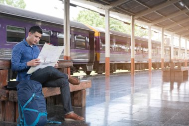 sırt çantası platformda tren istasyonunda oturan Asya adam. ba