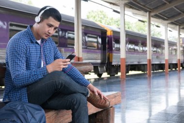 sırt çantası platformda tren istasyonunda oturan Asya adam. ba