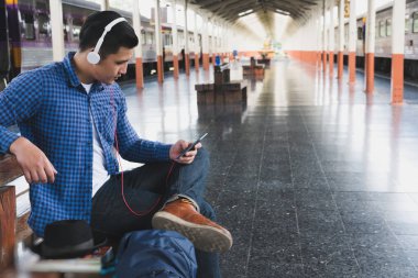 sırt çantası platformda tren istasyonunda oturan Asya adam. ba