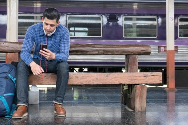 sırt çantası platformda tren istasyonunda oturan Asya adam. ba