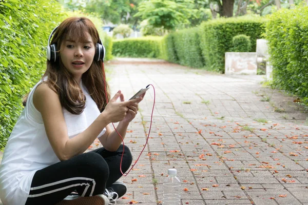 Азіатська жінка з навушниками. молода жінка тримає мобільний розумний — стокове фото
