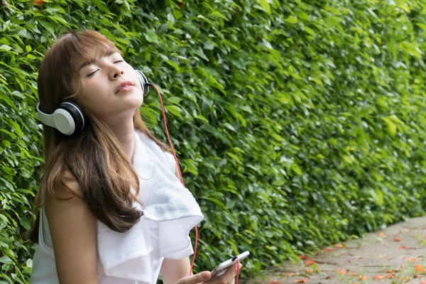 Mulher asiática com fones de ouvido. jovem fêmea segurando inteligente móvel — Fotografia de Stock