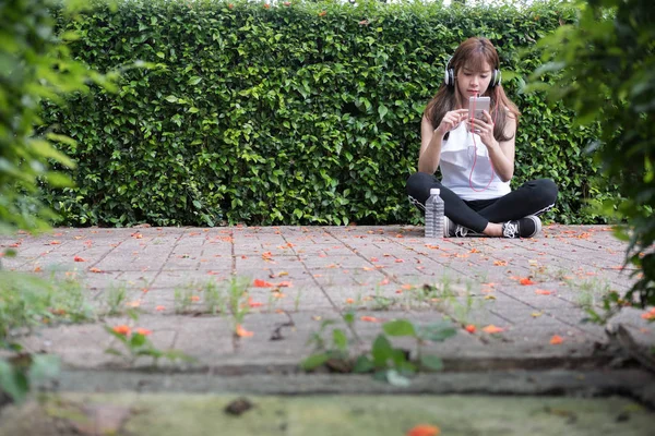 Asiatique femme avec casque. jeune femme exploitation mobile intelligent — Photo