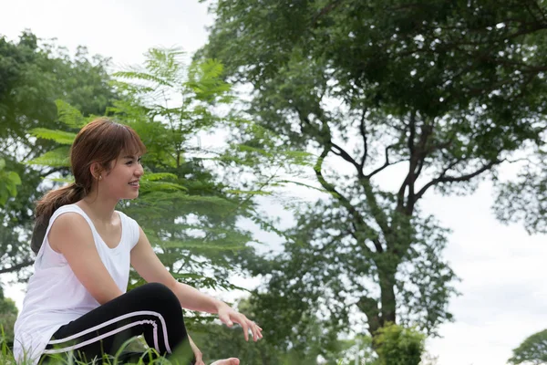 Молода азіатка практикує йогу на відкритому повітрі в громадському парку. здоровий — стокове фото