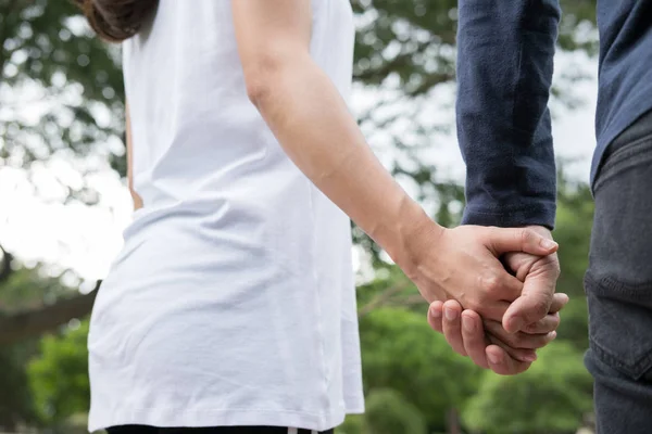 Feliz jovem casal de mãos dadas no jardim. Namorado e namorada — Fotografia de Stock