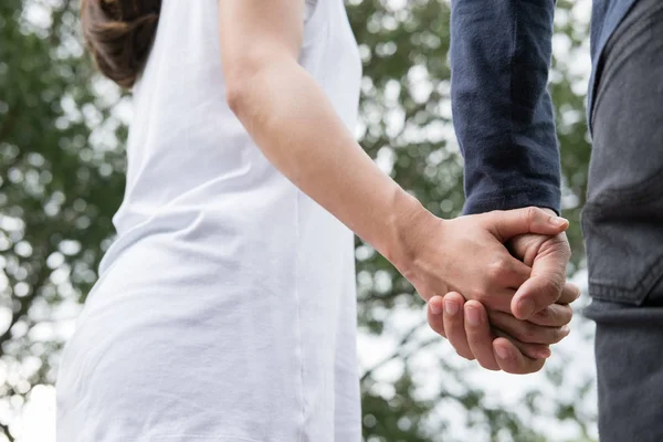 Feliz jovem casal de mãos dadas no jardim. Namorado e namorada — Fotografia de Stock