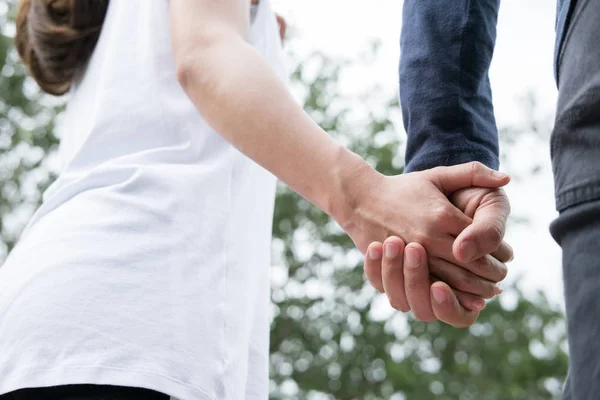 Glada unga par innehav händer i trädgården. Pojkvän och girlfr — Stockfoto