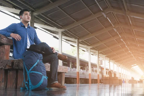 Asiático hombre con mochila sentado en plataforma en estación de tren. ba — Foto de Stock
