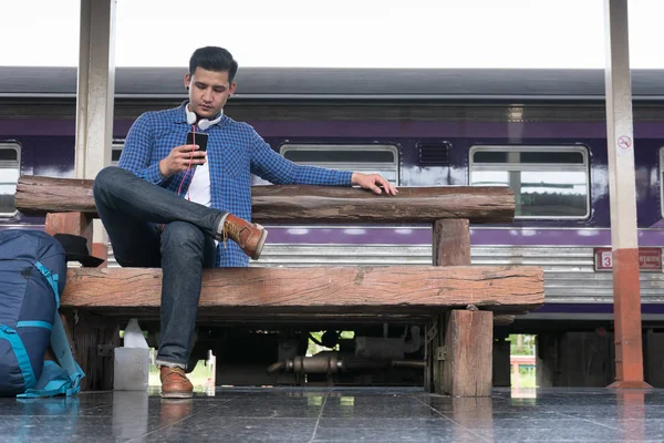 sırt çantası platformda tren istasyonunda oturan Asya adam. ba