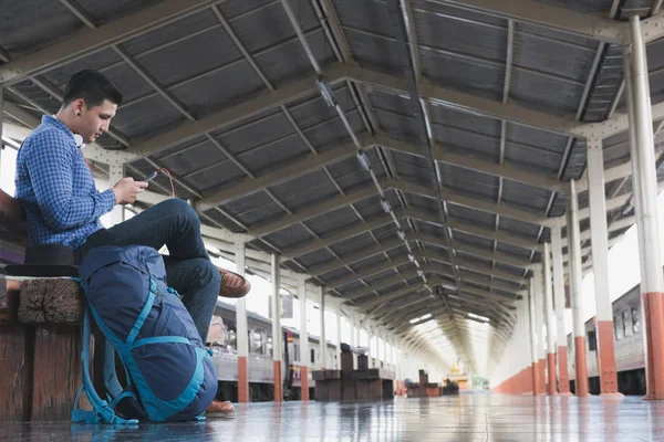 Asiático homem com mochila sentado na plataforma na estação de trem. b) — Fotografia de Stock