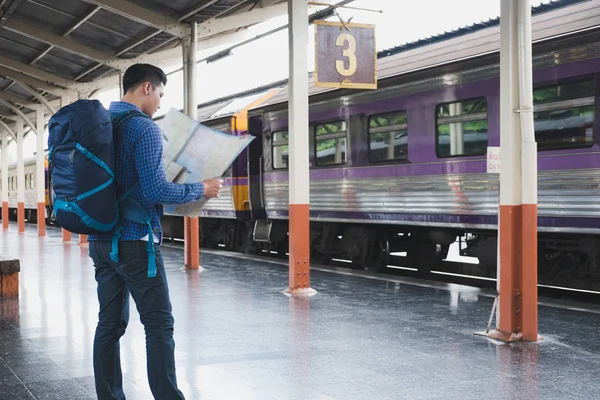 Asiatisk man med ryggsäck står på plattformen vid tågstationen. b — Stockfoto