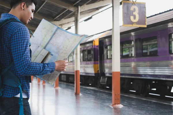 Asiatisk man med ryggsäck står på plattformen vid tågstationen. b — Stockfoto