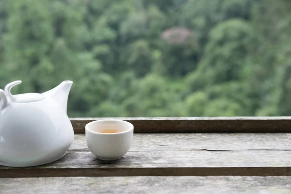 Weißer Tee in Tasse und Becher auf Holztisch mit grünem Naturhintergrund — Stockfoto