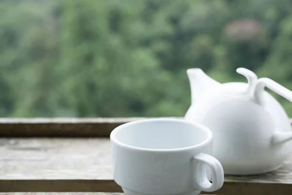 Weiße Teetasse und Becher auf Holztisch mit grünem Hintergrund — Stockfoto