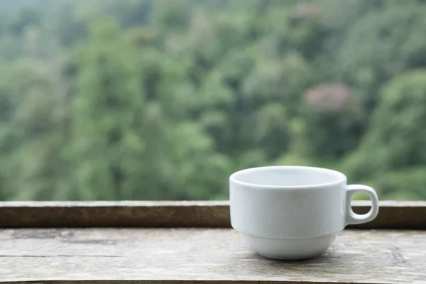 Weiße Teetasse auf Holztisch mit grünem Hintergrund — Stockfoto