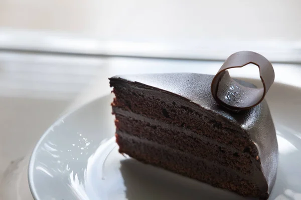 Bolo de chocolate escuro saboroso na placa branca. cacau delicioso fatiado — Fotografia de Stock