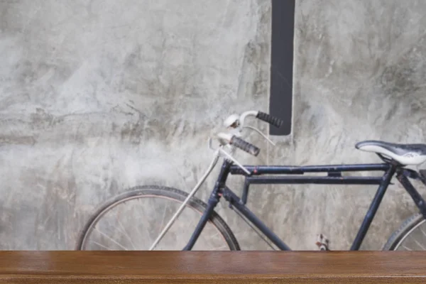 Svart cykel bredvid grå vägg med bord av trä för visning din — Stockfoto