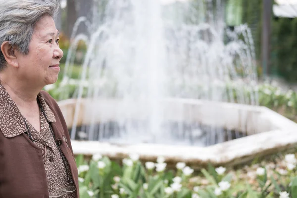 Mujer mayor asiática de pie cerca de la fuente en el jardín. ancianos seni — Foto de Stock