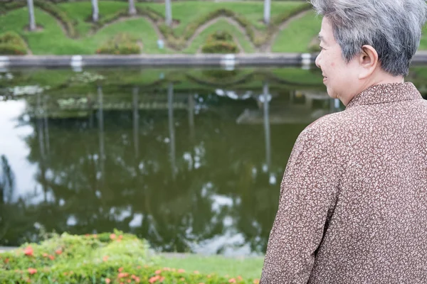 Aziatische oudere vrouw stond in de tuin. ouderen senior vrouwelijke rest — Stockfoto