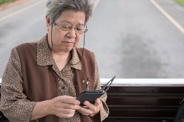 asian elder woman holding mobile smart phone on bus. elderly sen