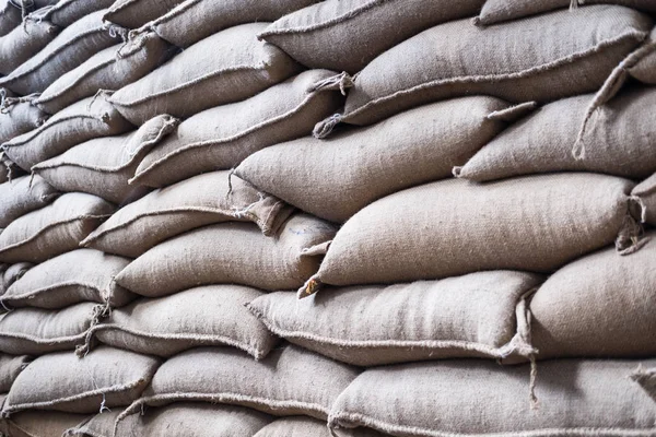 Sacos de cânhamo contendo grãos de café no armazém. sacos empilhados em — Fotografia de Stock