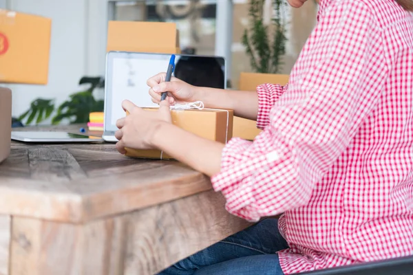 start up small business owner writing address on cardboard box a
