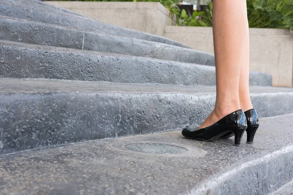 feet and leg of businesswoman wearing black high heel shoes goin