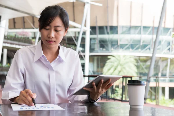 Mujer de negocios con tableta digital y resumen financiero gráfico sitt Imágenes de stock libres de derechos