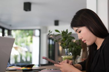 işyerinde iş kadını kullanım cep telefonu. genç kadın manifatura