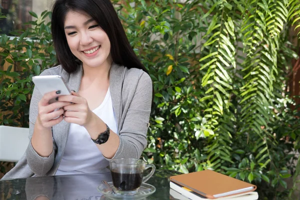 Азіатська жінка сидить у відкритому кафе. молода жінка дорослий використовує мобільний p — стокове фото