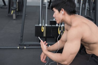 genç adam fitness merkezinde cep telefonu kullanın. erkek atlet liste